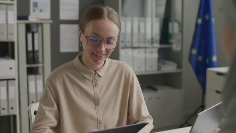 female visa officer examining documents and talking to applicant in consulate