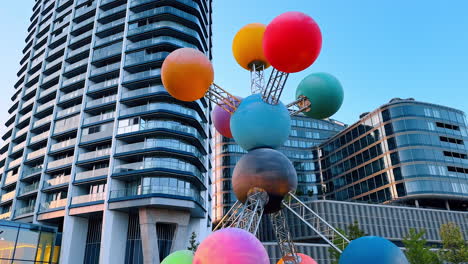 colorful spheres in urban landscape. a vibrant sculpture of spheres stands in an urban area, showcasing various colors against modern buildings in daylight