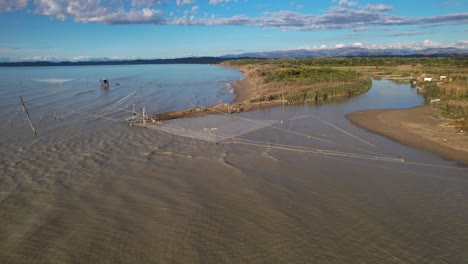 large fishing nets hang over the mouth of the river where it joins the sea water