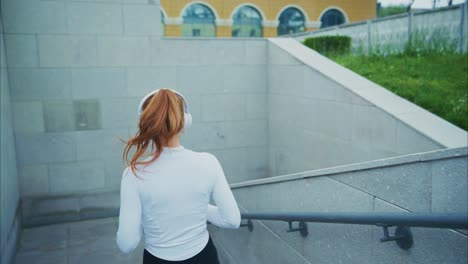 woman running up stairs with headphones
