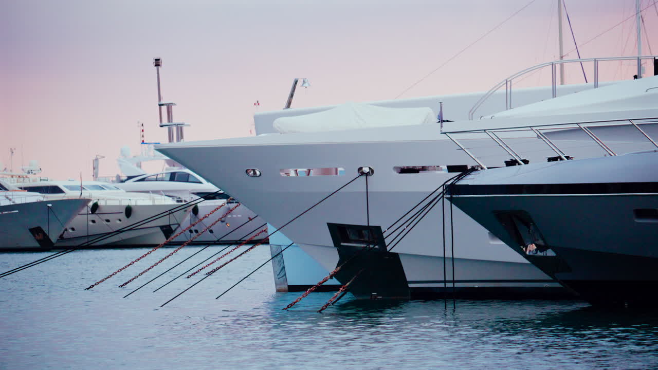 Three luxury yachts docked side by side in a calm marina, captured in soft daylight