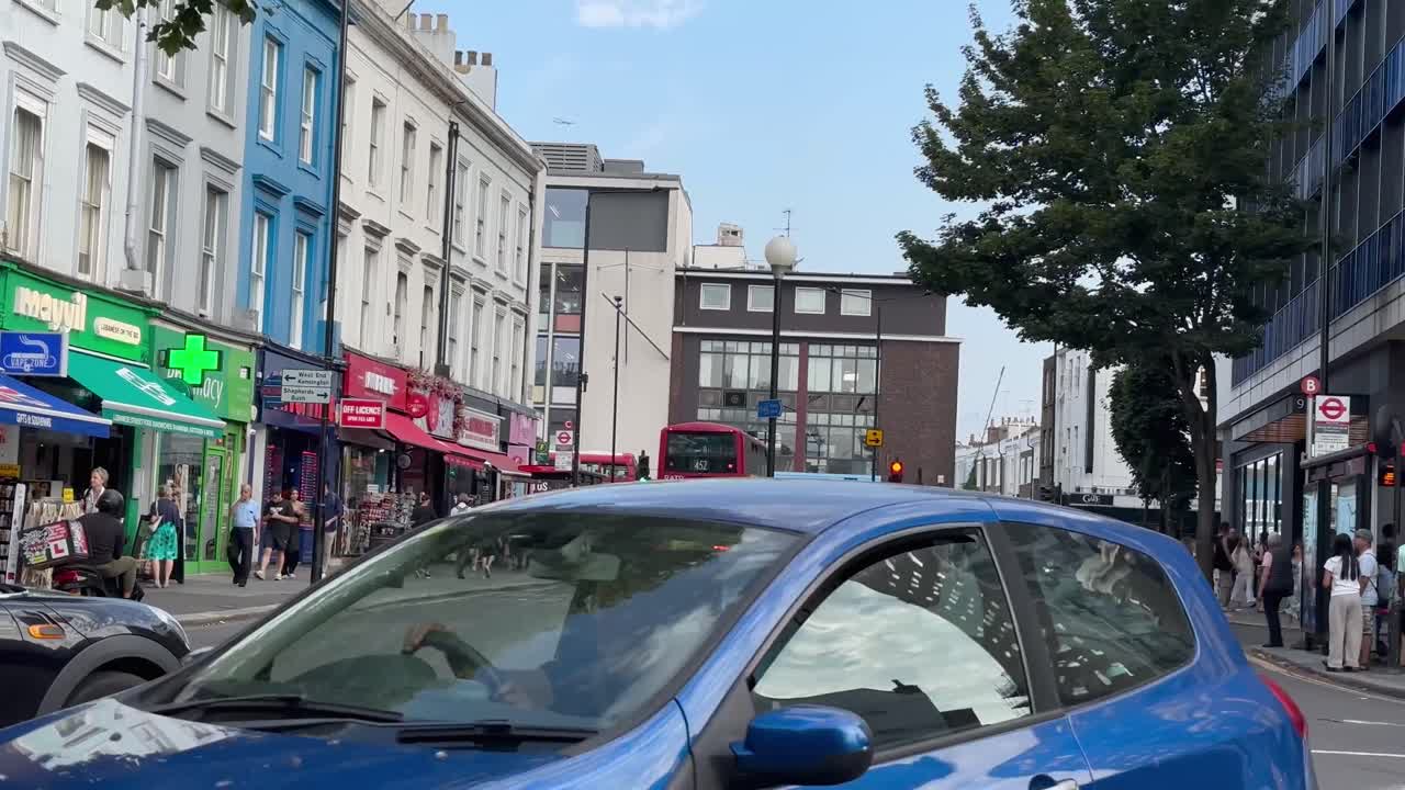 A busy London street with people walking and traffic, featuring a red double-decker bus