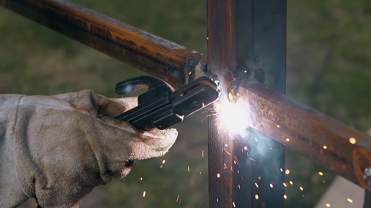 Nærbilde av bygger som sveiser rammeverket til et rustent metallgjerde