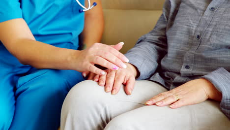 close up of female nurse holding senior woman hand