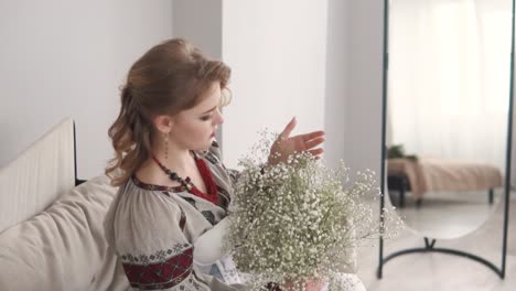 schöne junge frau in einer geborbenen authentischen ukrainischen bluse und korsett-pose, die einen blumenstrauß hält