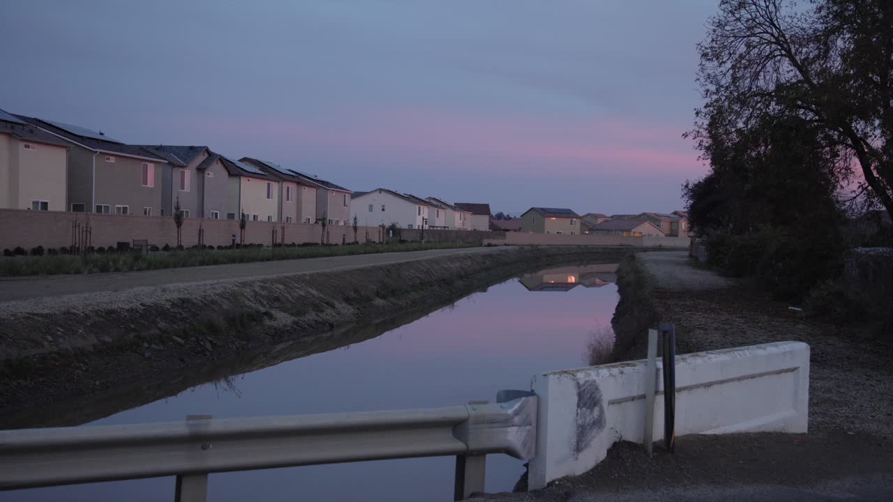 미국 캘리포니아주 클로비스의 배경에 집들이 있는 운하 위의 파스텔 하늘