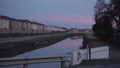 a pastel sky over a canal with houses in the background in clovis, ca, usa