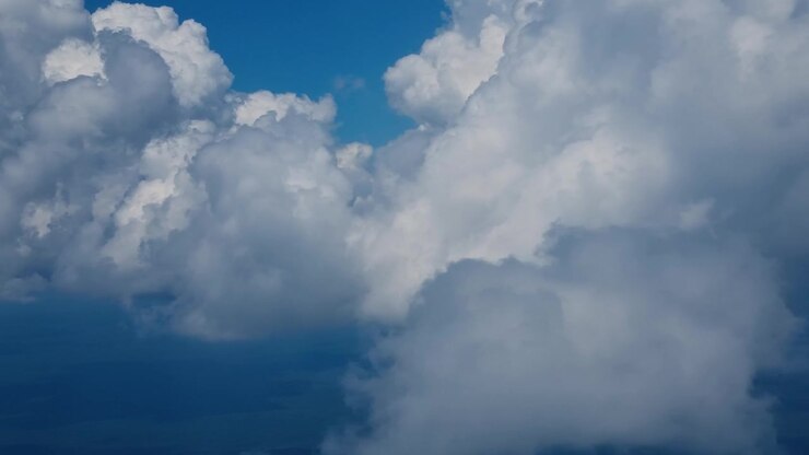 Passenger view from an airplane flying over Argentina above a vast layer of white clouds, with a clear blue sky creating a peaceful aerial travel scene