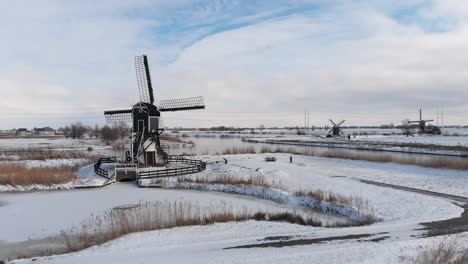 Canales-De-Molinos-De-Viento-Holandeses-Cubiertos-De-Nieve-Y-Tierra-De-Pólder,-Vista-Aérea-De-Invierno-Frío