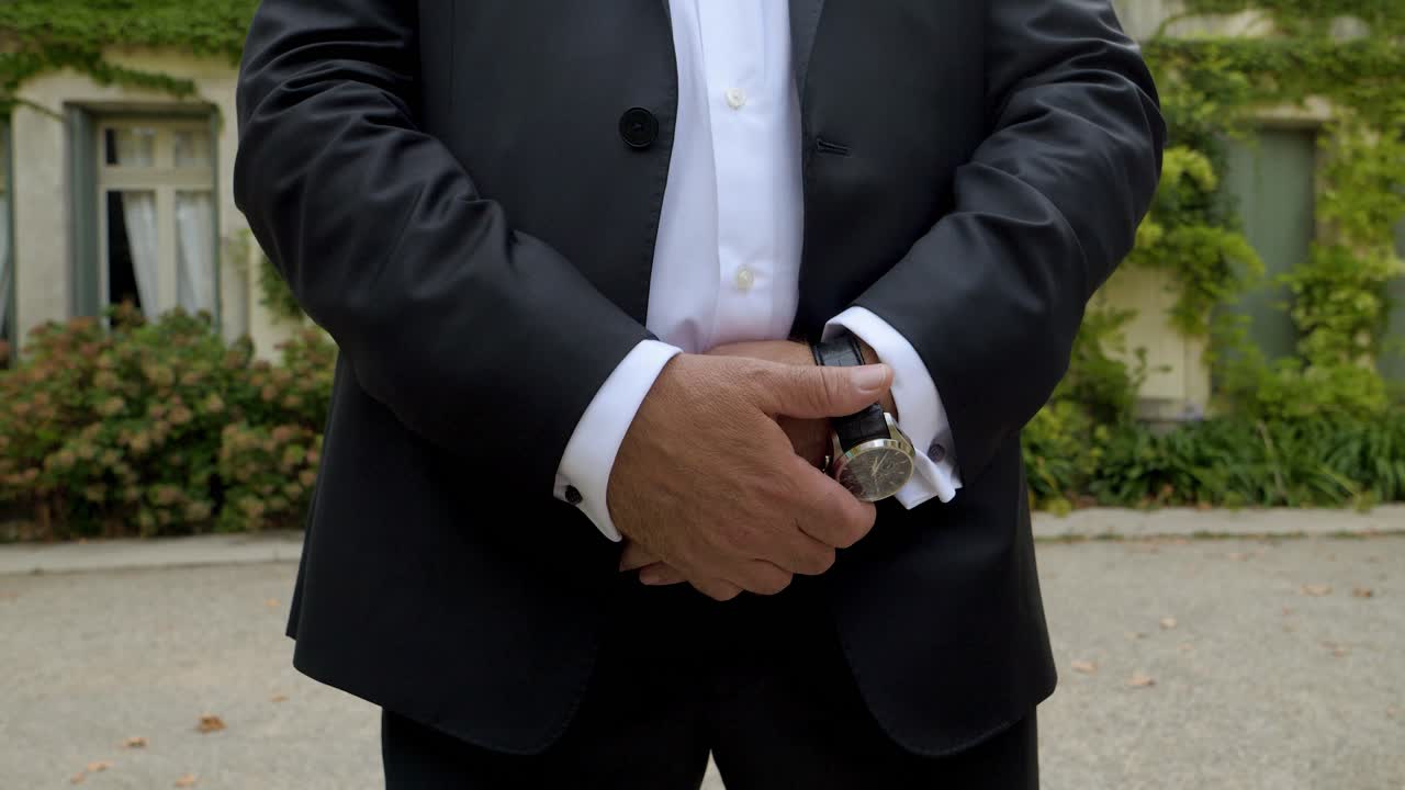 primer plano del novio en traje de boda que consiste en un traje y un reloj bien ajustados