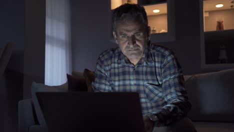 freelancer man at home looking at laptop at night, working.