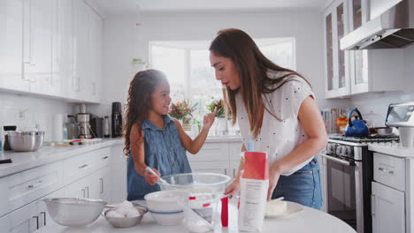 Mother-and-daughter-preparing-cake-mix,-tasting-it-and-dabbing-it-on-each-other’s-noses,-close-up