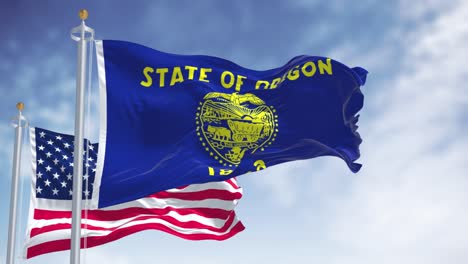 the oregon state flag waving along with the national flag of the united states of america