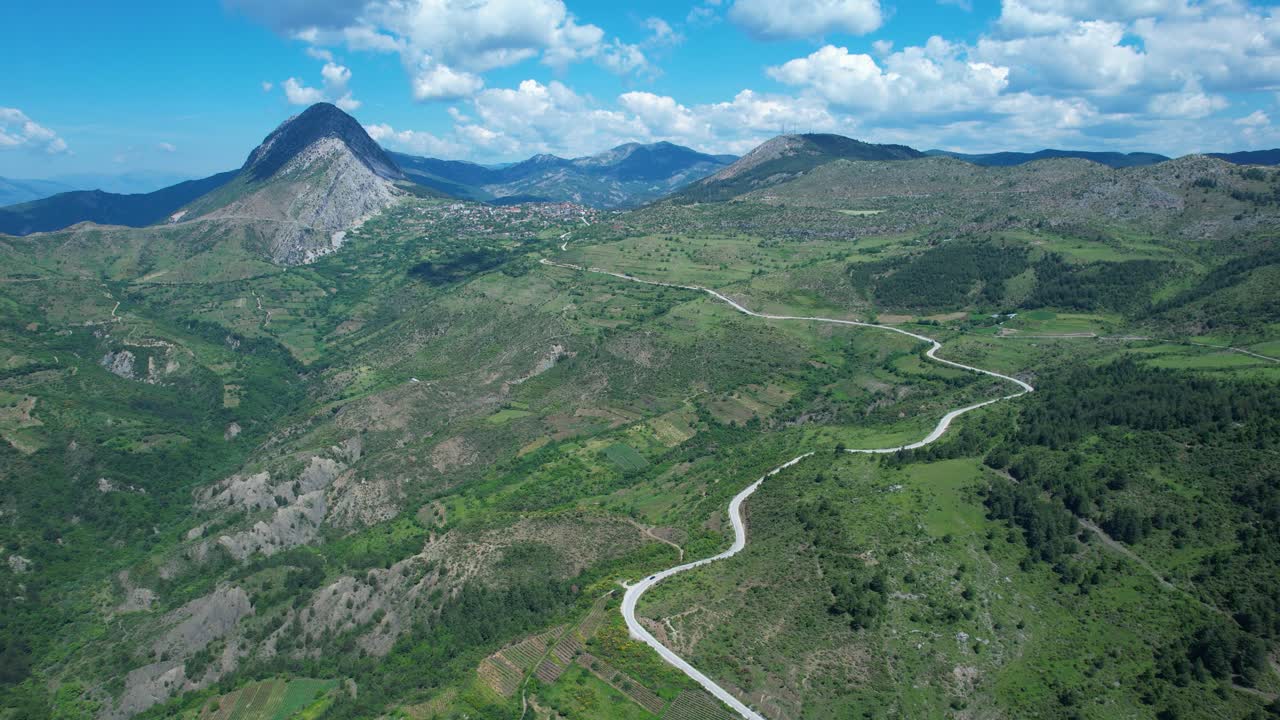 Mountains range covered in green lush vegetation winding road leads to scenic Leskovik Albania panorama
