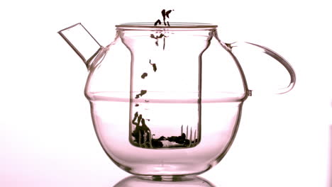 Loose-tea-falling-into-glass-teapot-