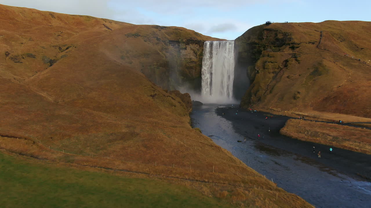 drone cinematográfico skogafoss cascada islandia pan hacia adelante movimiento con pájaros, arco iris y luz del sol de la tarde