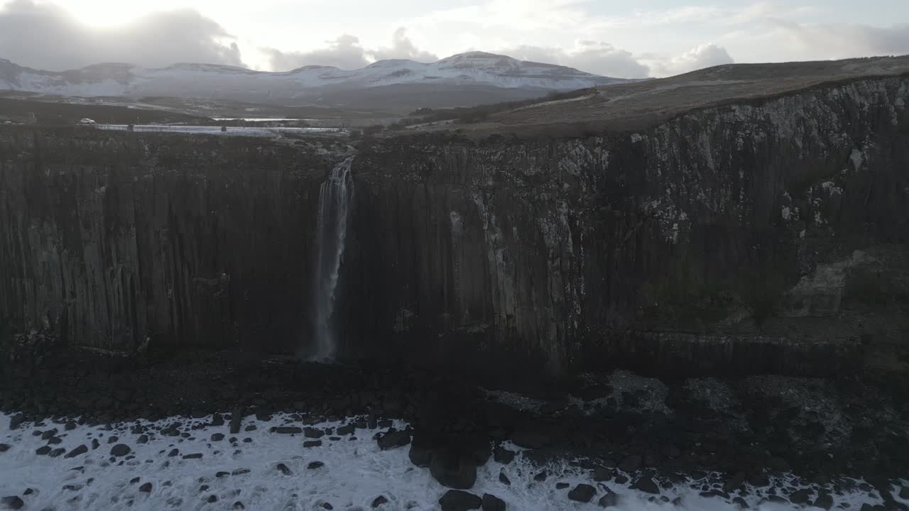 majestuosa cascada de kilt rock en escocia con manchas de nieve, paisaje sereno bajo cielos nublados
