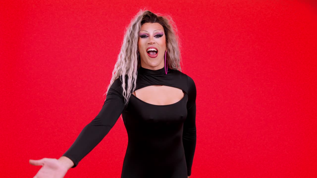 Drag queen in posa e che manda baci su sfondo rosso