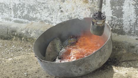 fire lighter to melt lead in a pot in rustic way to make fishing sinkers weights