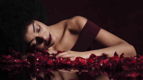 portrait-beautiful-african-american-woman-with-afro-red-rose-petals-blowing-sensual-female-looking-seductive-dreaming-of-intimate-fantasy-romance-indulging-desire-in-valentines-day-concept