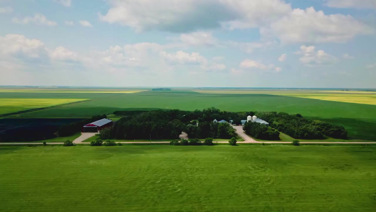 Statisk luft-timelapse af en landlig hvedefarm, mens skyer bevæger sig over himlen, og skygger glider over landskabet
