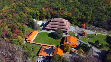 an aerial view of the chuang yen monastery on a sunny fall day, the leaves of the trees begin to change for the autumn season