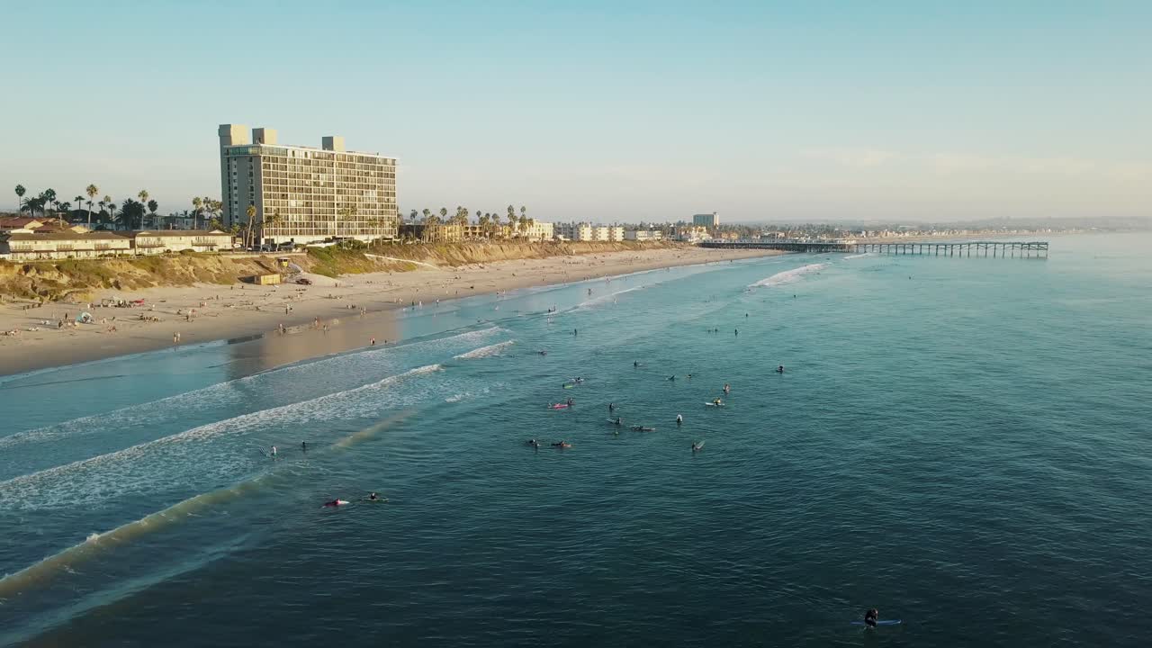 샌디에고의 태평양 해변과 크리스탈 부두의 환상적인 조감도 - 4k 드론 샷 - 일몰 동안 서핑