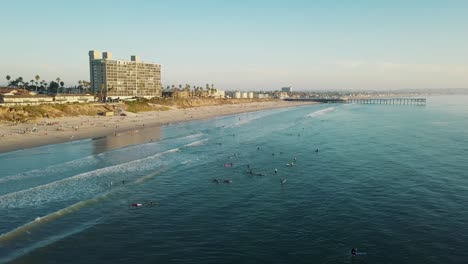 fantastic birds eye view of the pacific beach and crystal pier of san diego - 4k drone shot - surfing while sunset