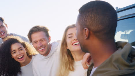 Young-adult-friends-standing-by-their-car-talking