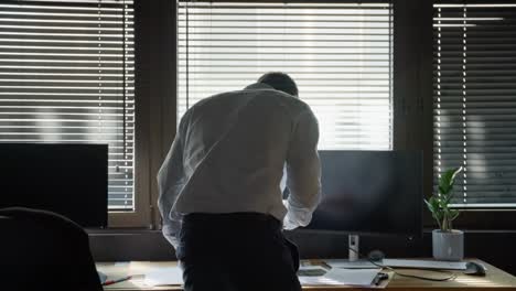 Suited man, agent, spy, or thief, at office desk, scanning confidential files while anxiously glancing back, fearing someone’s arrival. Back shot secrecy, tension, crime, and classified intelligence.