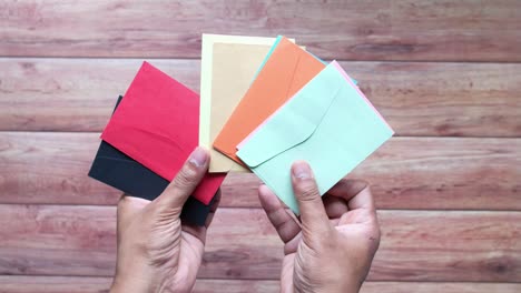 manos sosteniendo sobres de colores variados