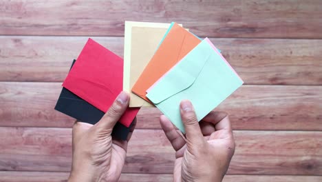 hands holding assorted colored envelopes