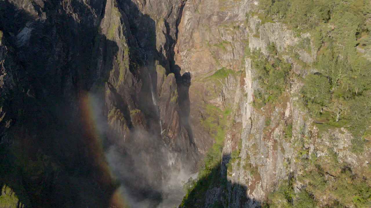 Mist at bottom of Vorinsfossen falls creating a rainbow, drone view