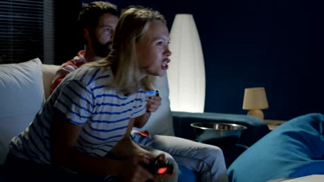 pareja expresiva jugando a videojuegos en casa