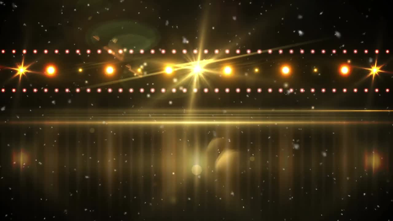 White particles floating over golden spots of light and disco lights against black background