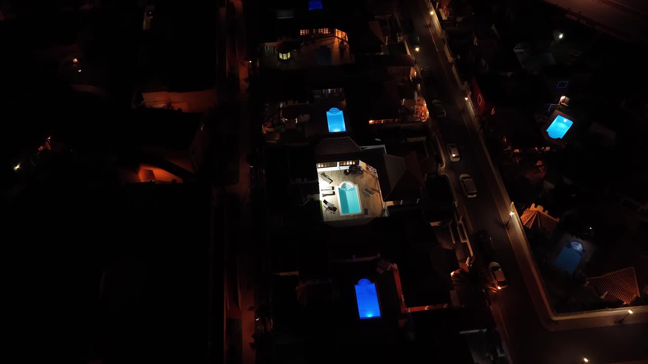 Drone dolly-in over a luxury villa at night in Fuerteventura, Canary Islands, showcasing illuminated pools, modern architecture, and tranquil residential design