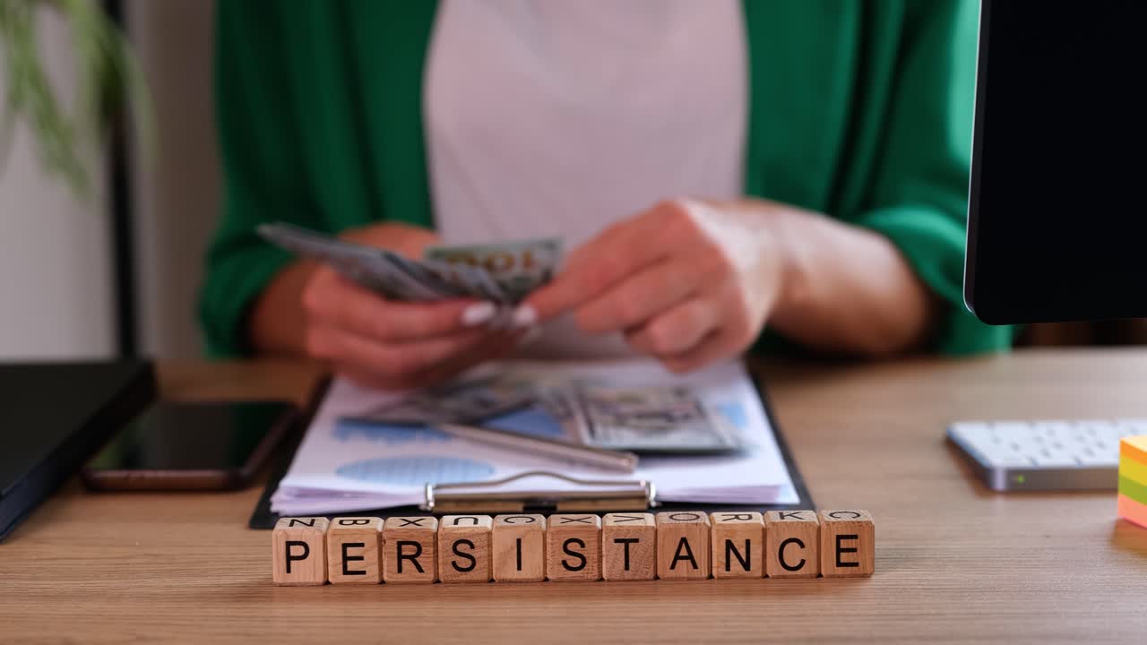 Word persistence made of cubes against woman counting money