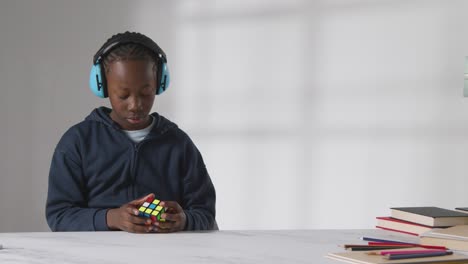 studio shot of boy on asd spectrum solving puzzle cube wearing ear defenders 3