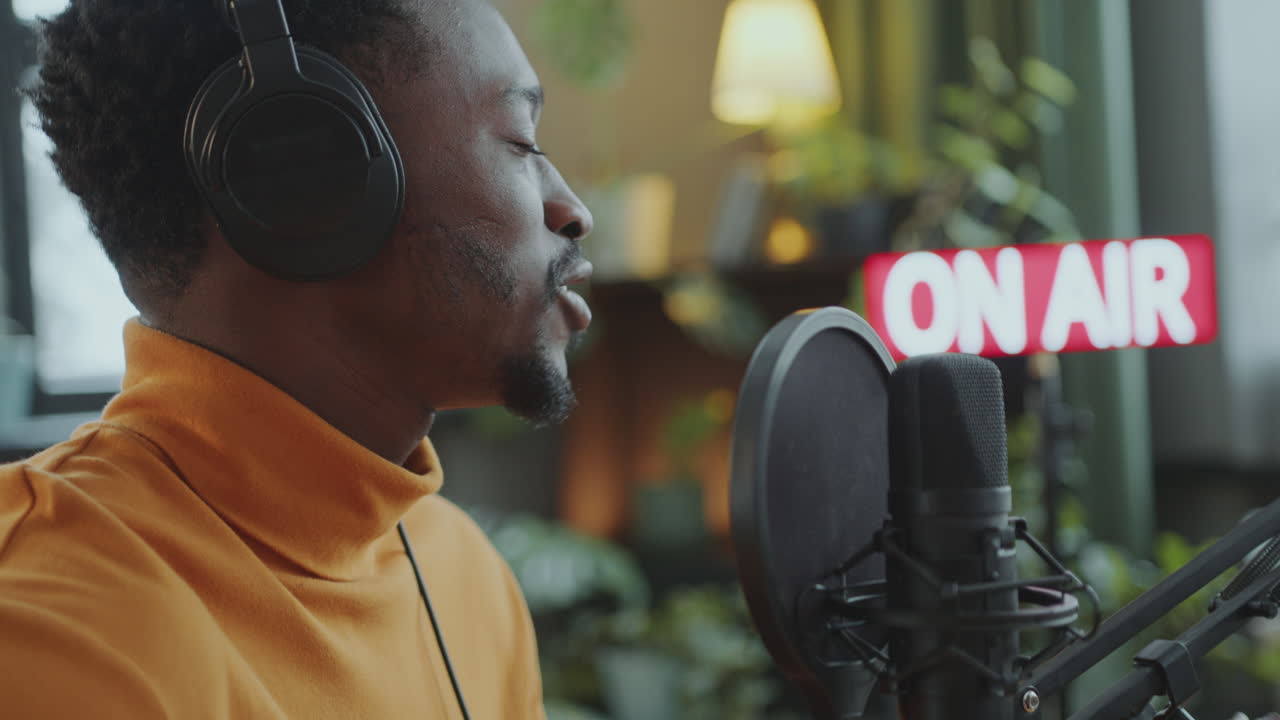 hombre negro cantando a la guitarra durante un programa de radio en un estudio de radiodifusión