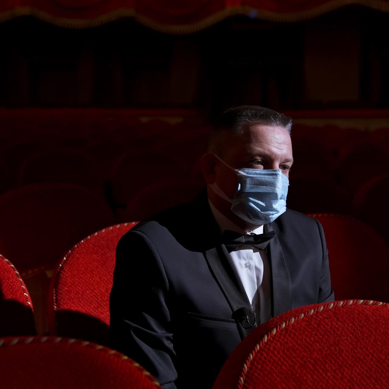 Actor in medical mask on theatre. Empty classic theater