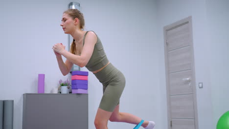 remote worker performs fitness routines in a modern gym, using a purple yoga mat and a cabinet filled with colorful yoga blocks in the background