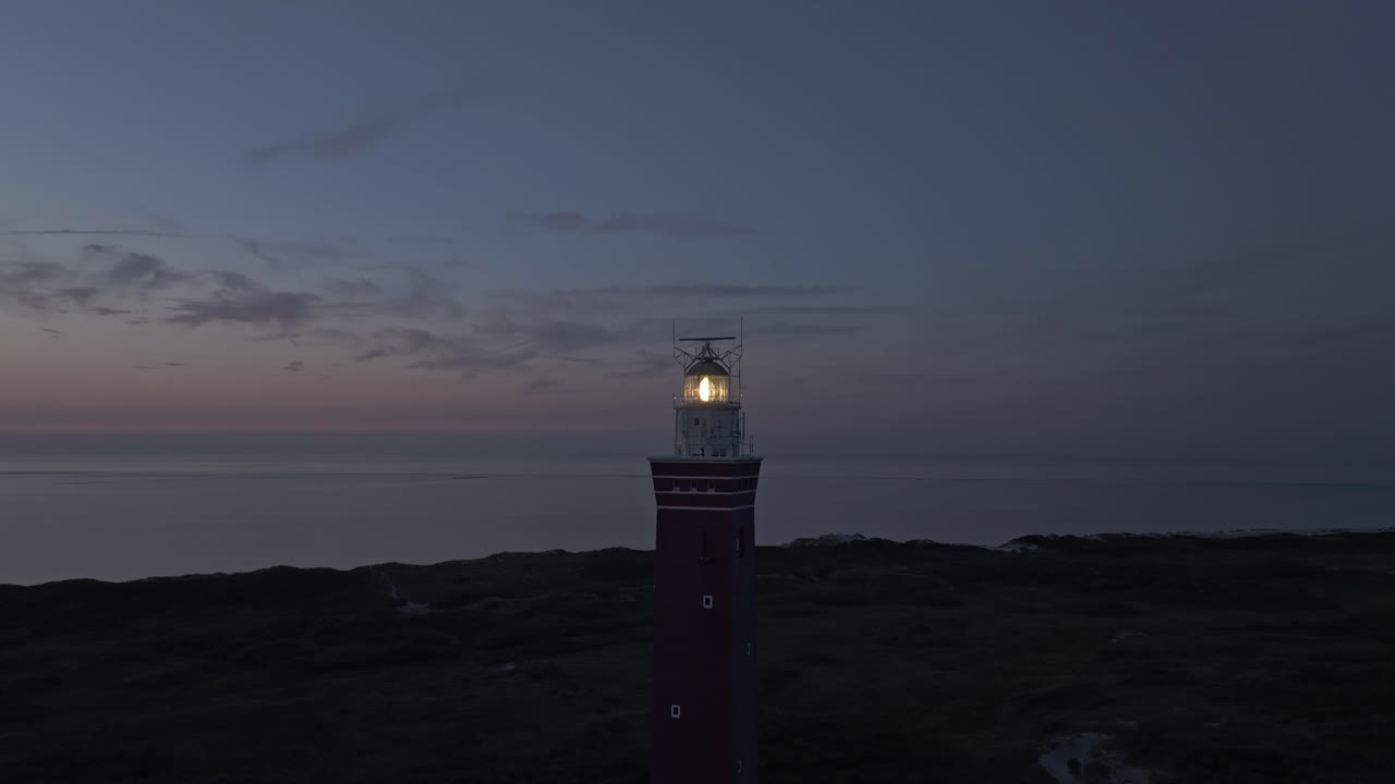 tomada de órbita del faro westhoofd con la luz encendida durante la puesta del sol, aérea