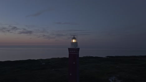 tomada de órbita del faro westhoofd con la luz encendida durante la puesta del sol, aérea