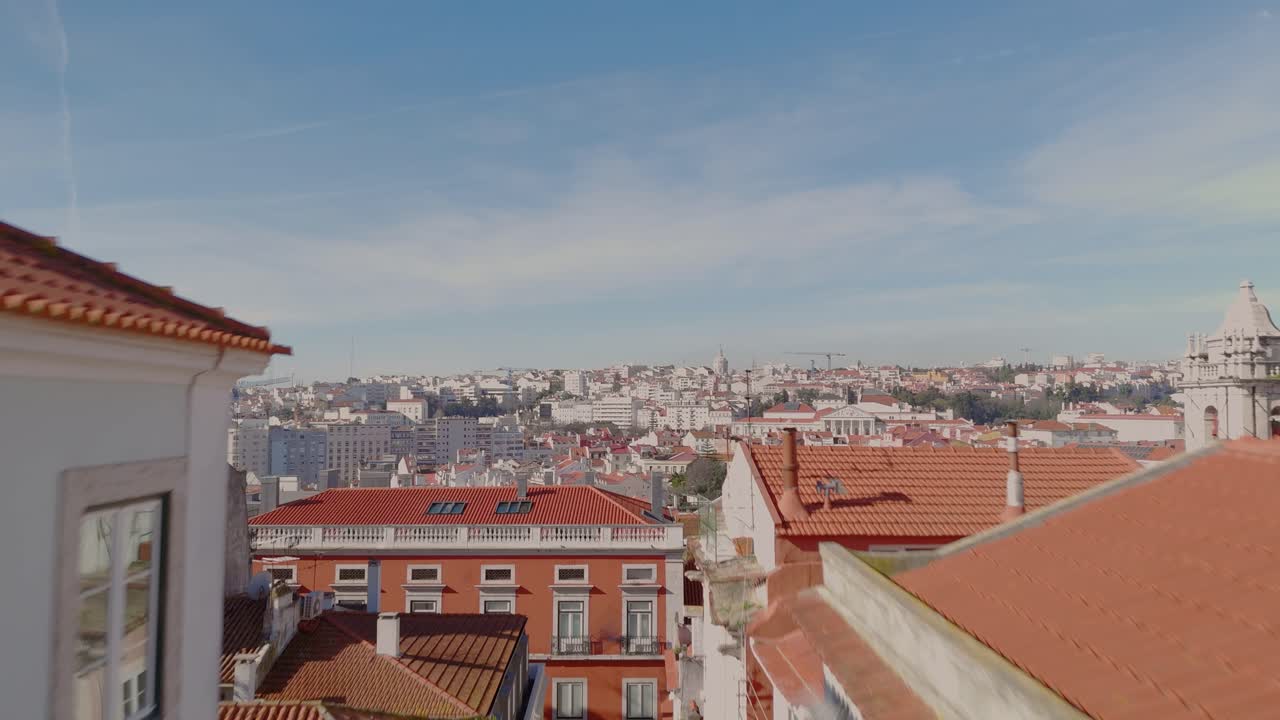 Dolly aereo si alza tra uno stretto vicolo di edifici per rivelare i suggestivi tetti storici di Lisbona, Portogallo