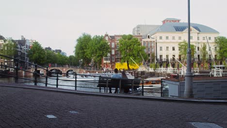 couple relaxing on a bench by a canal in amsterdam