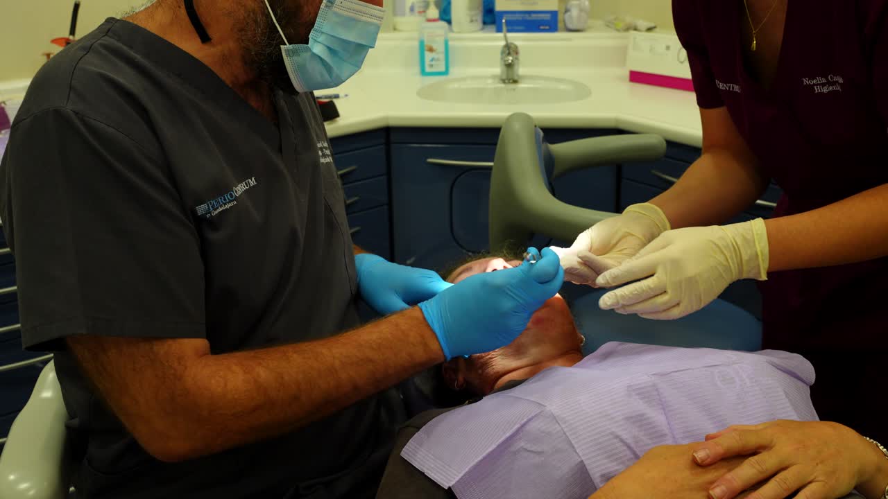 médico odontólogo quitando los puntos de sutura de las encías de un paciente