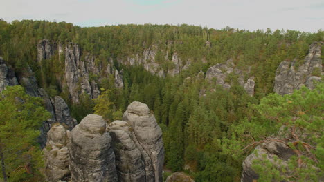 elbsandsteingebirge sachsen elbe sandstone formations rising above dense green forests mountains, under a blue sky with scattered clouds, showcasing the region’s natural beauty and rugged terrain