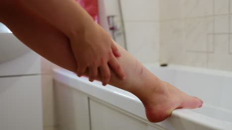 close-up of leg placed on bath sink with hand massaging it, focusing on skincare routine, moisturizing, healthy skin, self-care, smooth skin, rejuvenation, relaxation, body-care moment