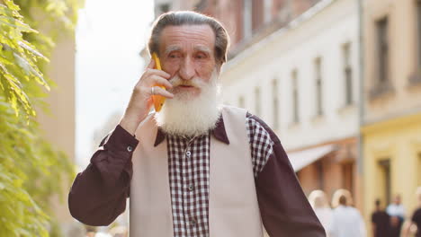 happy man grandfather having remote conversation talk on smartphone good news gossip in city street