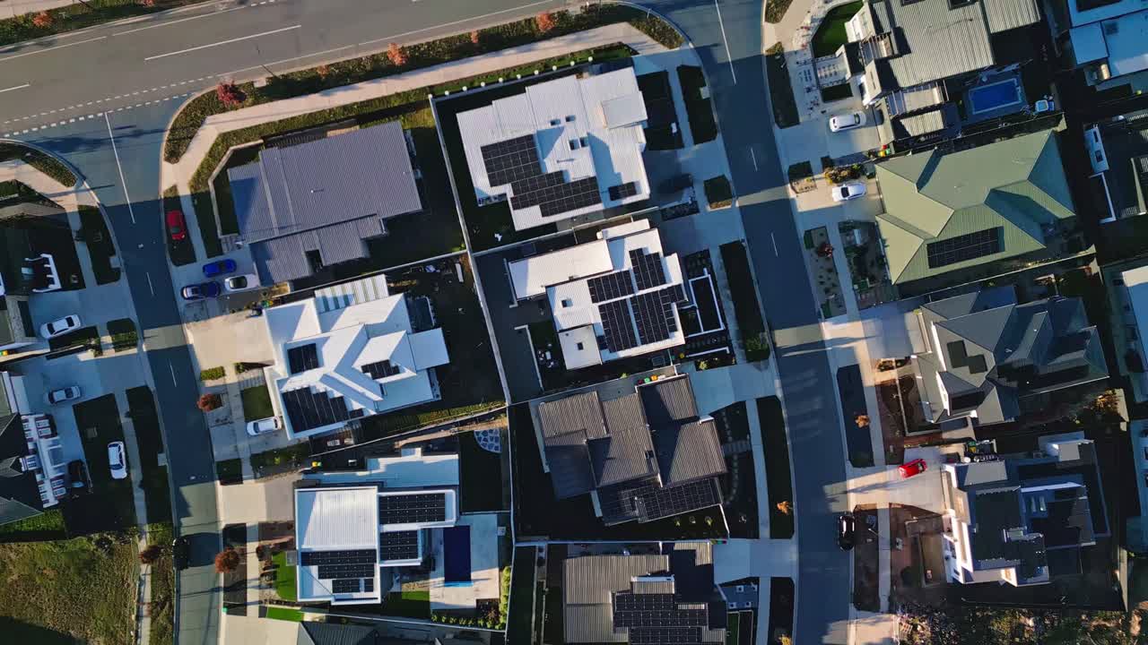 Aerial view directly over rooftops of new homes in Canberra, many fitted with solar panels in a modern housing estate.